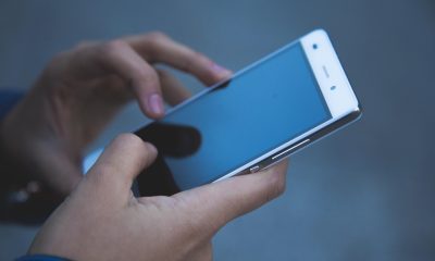手机屏幕特写展示九博体育App登录界面，手指正在点击登录按钮